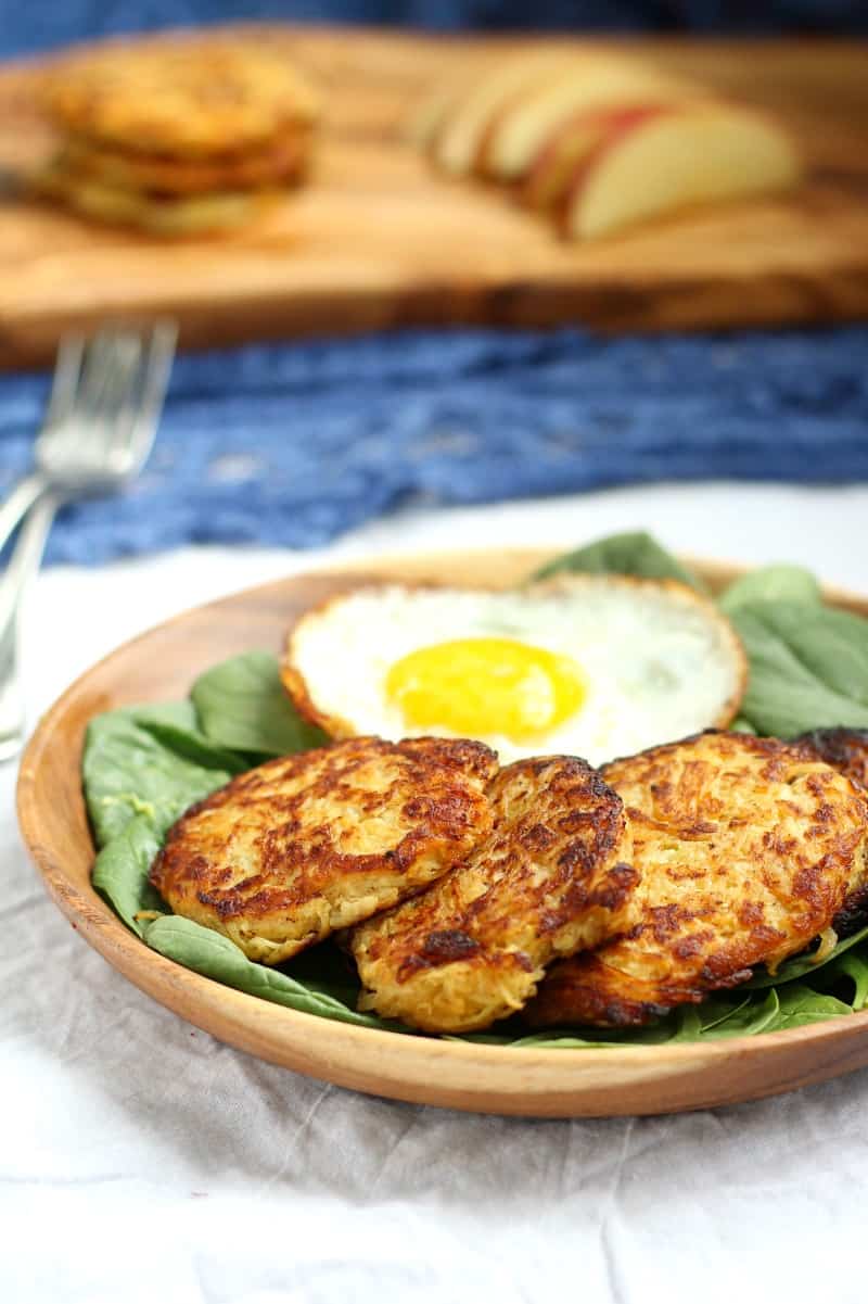 spaghetti squash apple fritters and a fried egg over a bed of spinach in a bowl