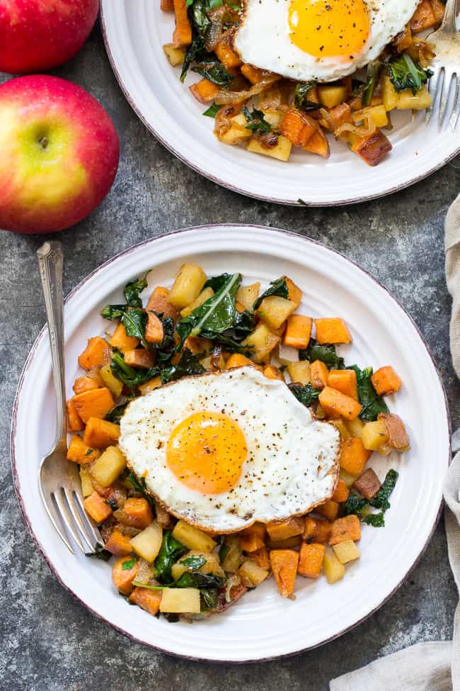 two plates of sweet potato, apple and kale hash with fried eggs on top