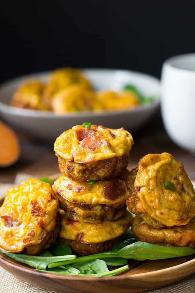 sweet potato bacon egg muffins stacked on a bed of greens