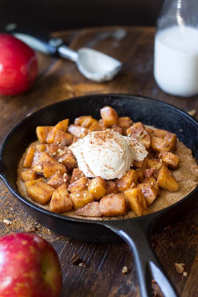 cookie topped with cooked apples and ice cream in a cast iron skillet