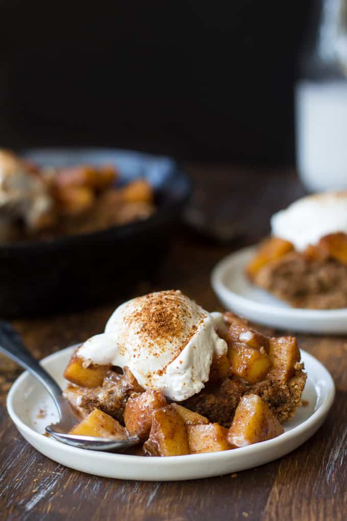 a portion of snickerdoodle skillet cookie topped with ice cream and cinnamon on a white plate