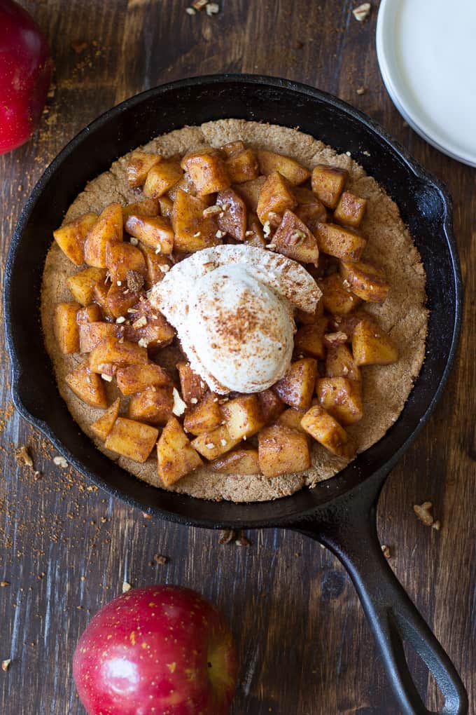 overhead shot of a cast iron skillet with a cookie base topped with cinnamon apples and ice cream