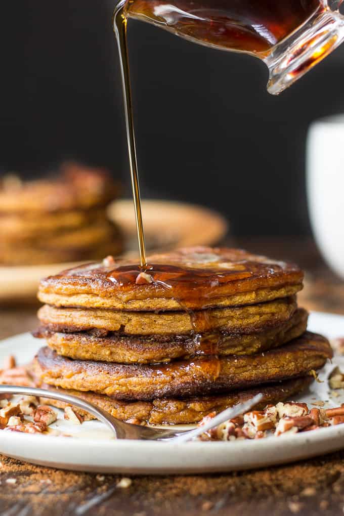 syrup pouring over a stack of five paleo pumpkin pancakes