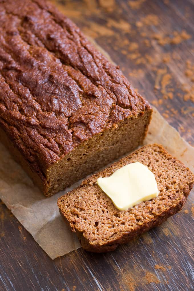 a loaf of pumpkin bread with one piece sliced off with a pat of butter