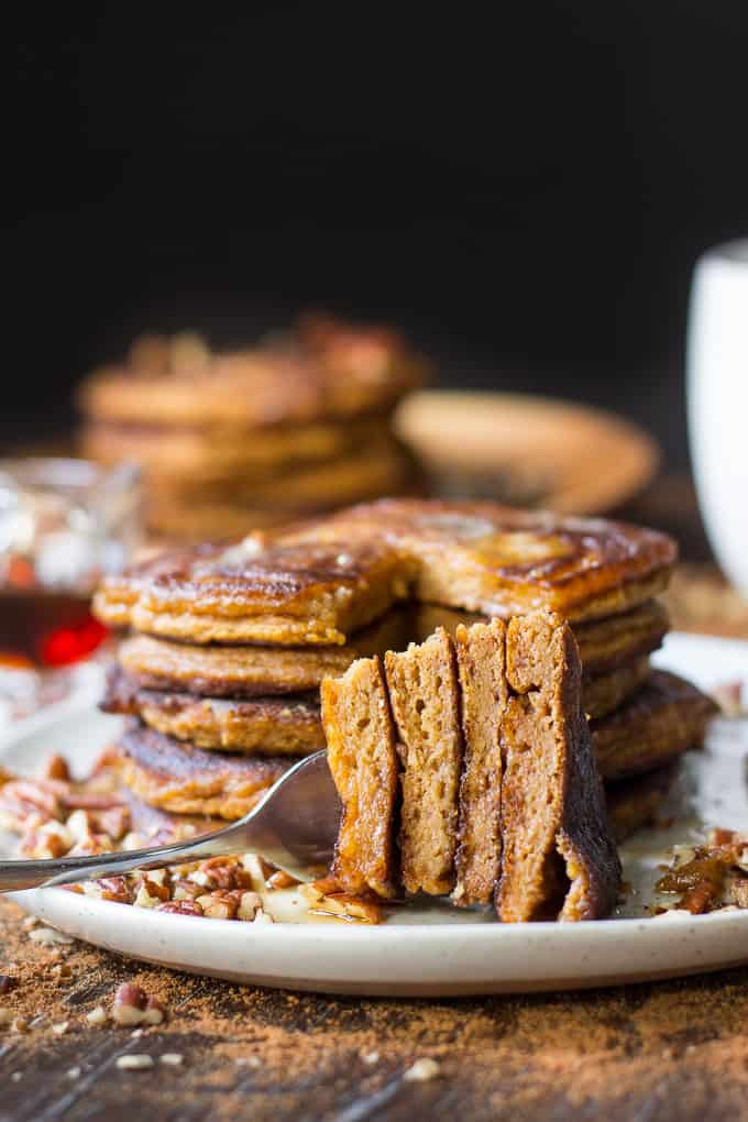 a bite of paleo pumpkin pancakes on a fork aside the stack of pancakes