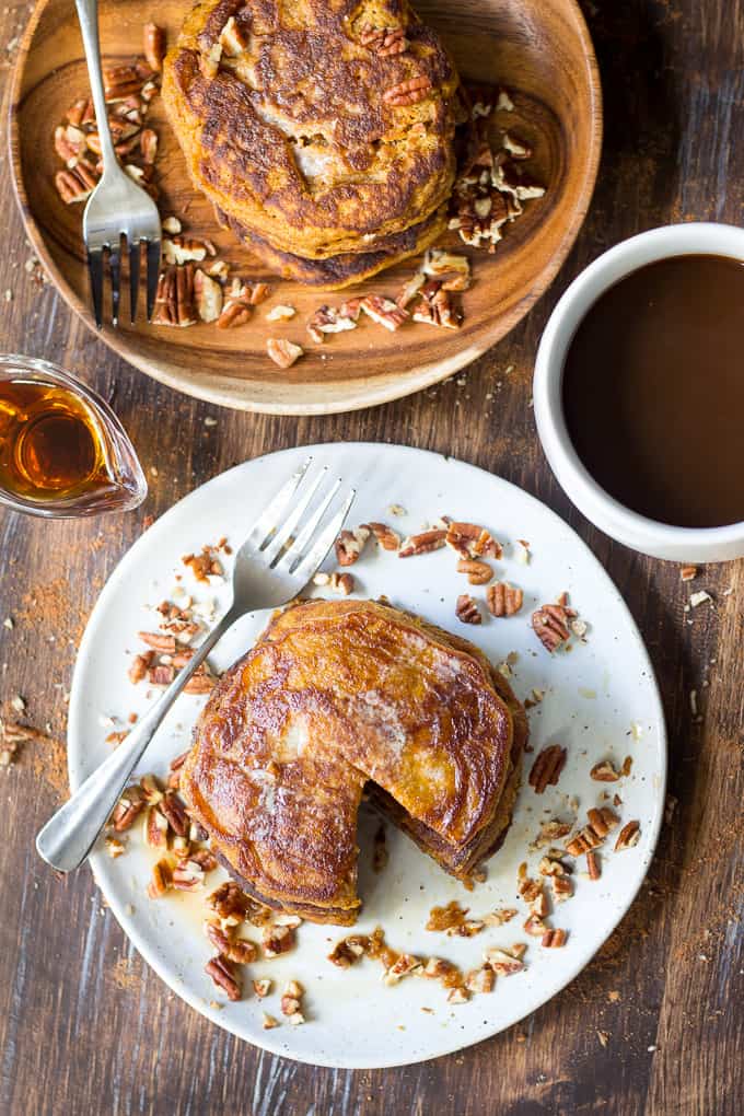 overhead view of two plates of stacks of pancakes with chopped pecans for garnish