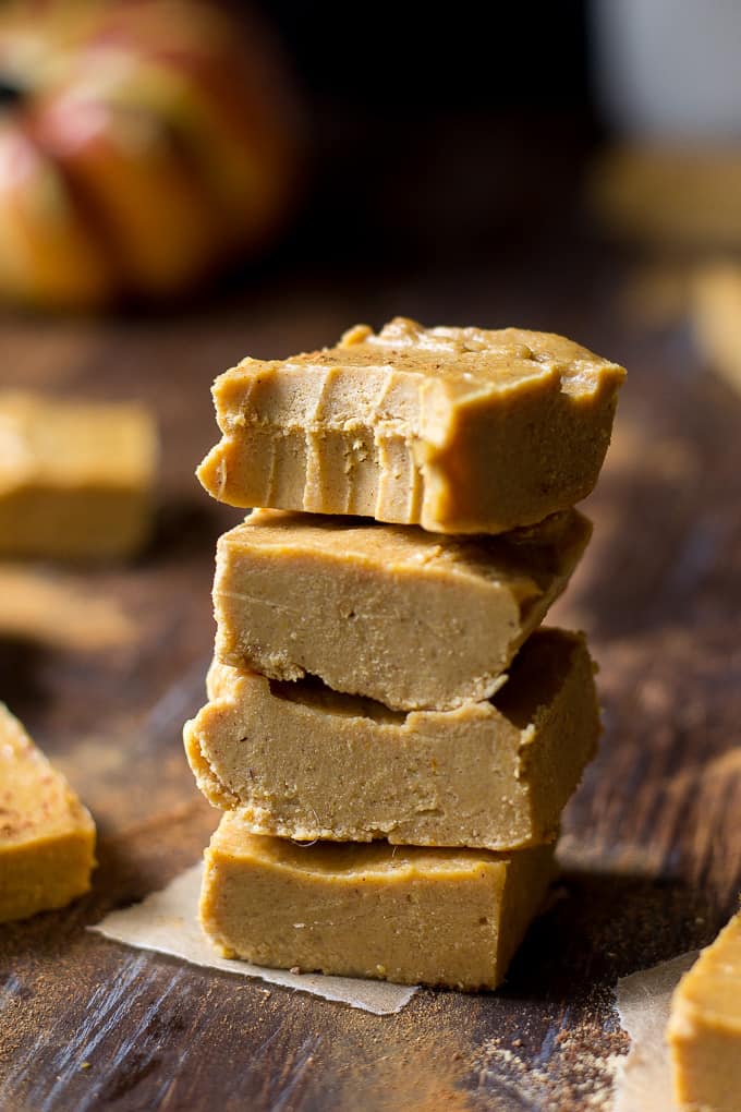 a stack of four pieces of pumpkin flavored fudge. A bite is taken from the top piece.