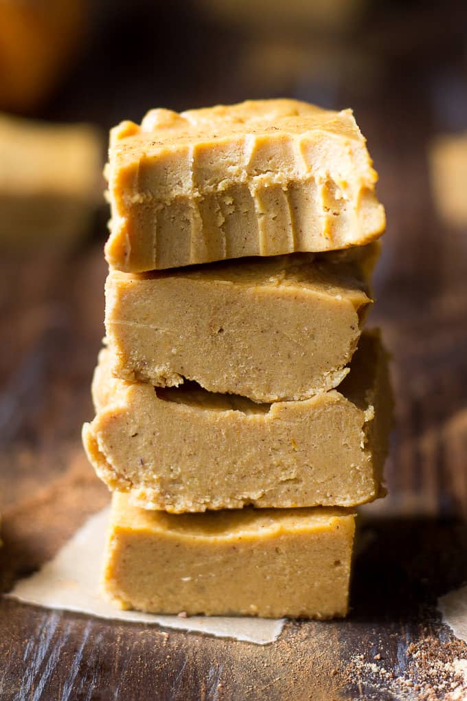 four squares of light orange-brown fudge stacked on a board