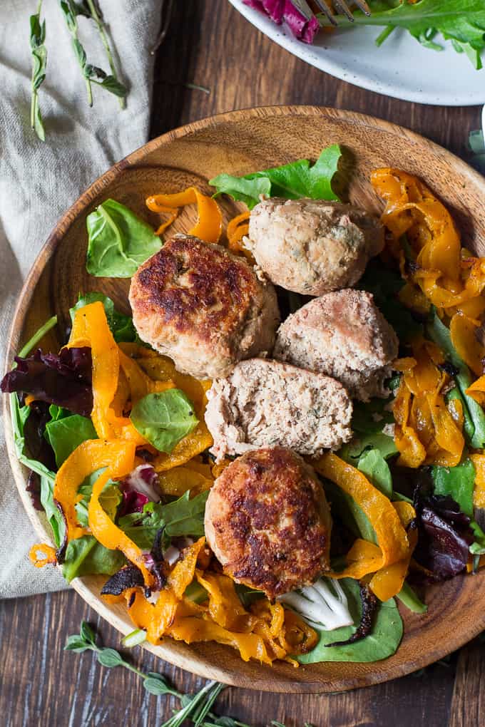 overhead view of a wooden bowl filled with salad and a few sliced turkey meatballs