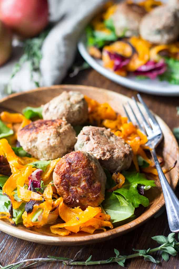 closeup view of a wooden bowl filled with salad and topped with meatballs