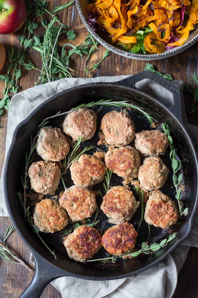 cooked turkey meatballs in a cast iron skillet with fresh herb sprigs