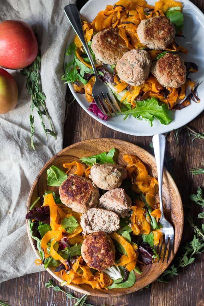 two bowls of meatballs over sweet potatoes and salad with forks