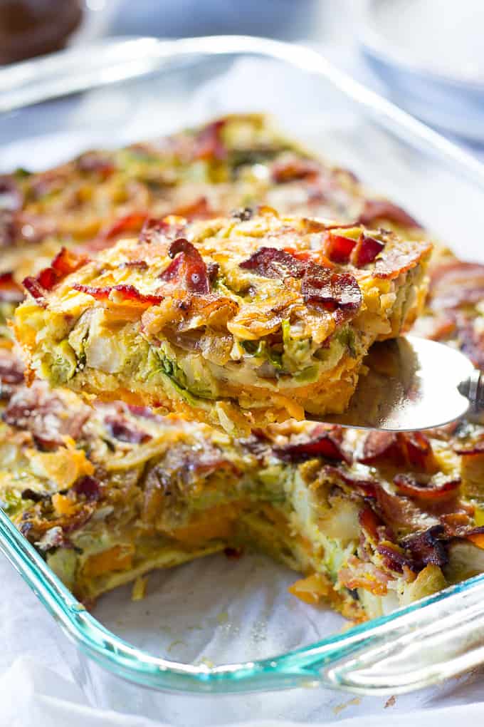 a slice of breakfast casserole being taken out of a casserole dish with a serving tool