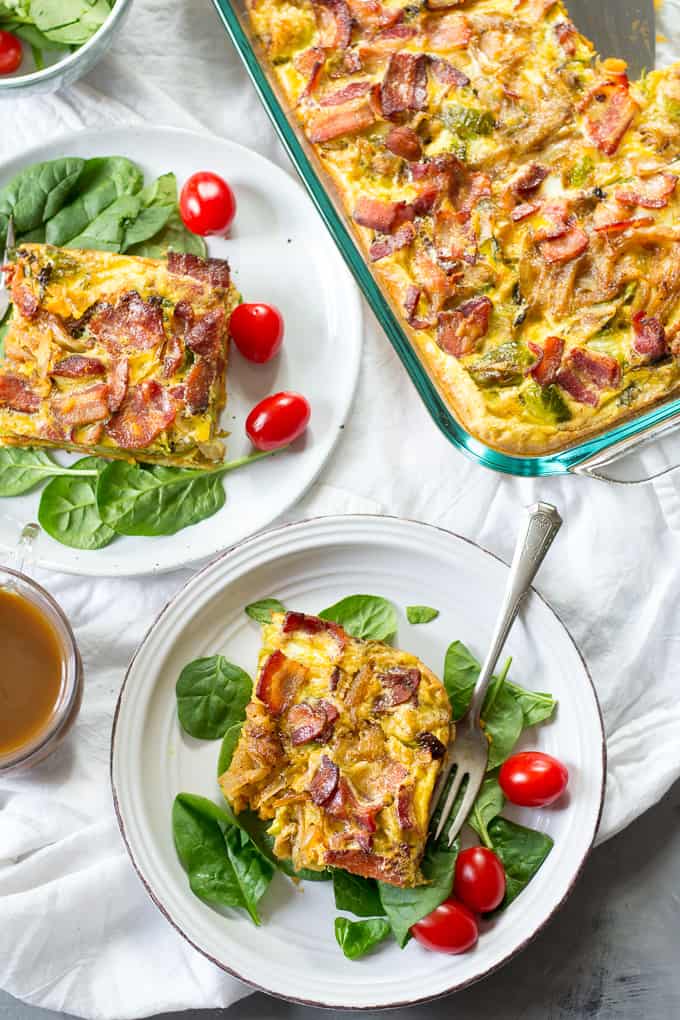 breakfast casserole in a dish with two slices of casserole on plates of spinach