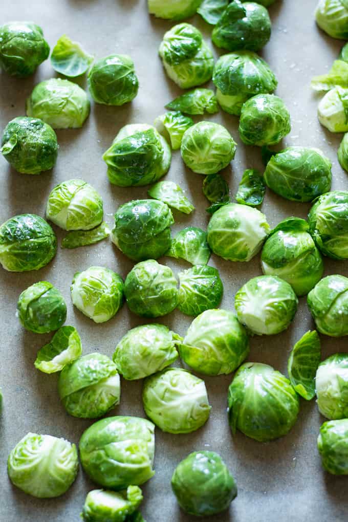 bright green uncooked Brussels sprouts scattered on parchment paper