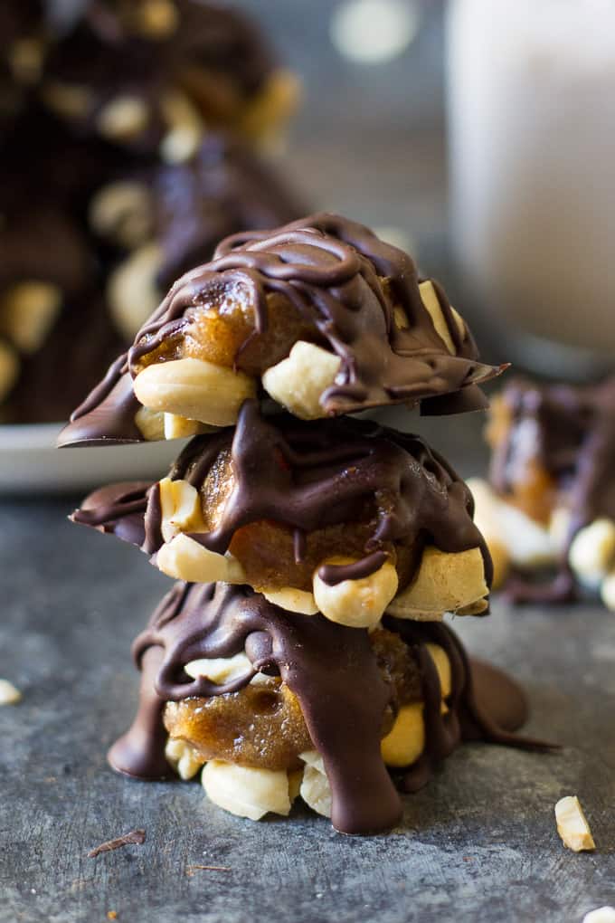 a stack of three chocolate covered caramel cashew candy clusters