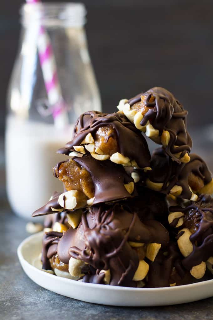a pile of turtle candy clusters on a plate with a bottle of milk in the background
