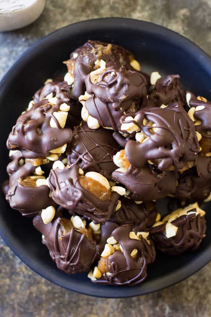 paleo chocolate turtle candy clusters piled in a dark blue bowl