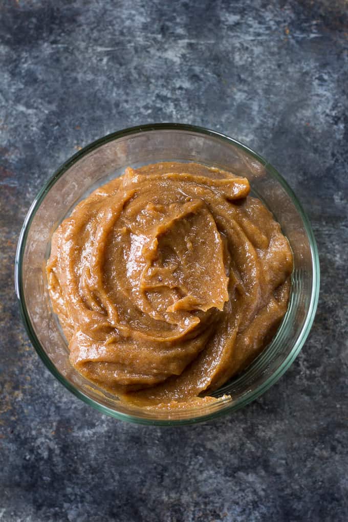 tan caramel swirled in a glass bowl on a stone background