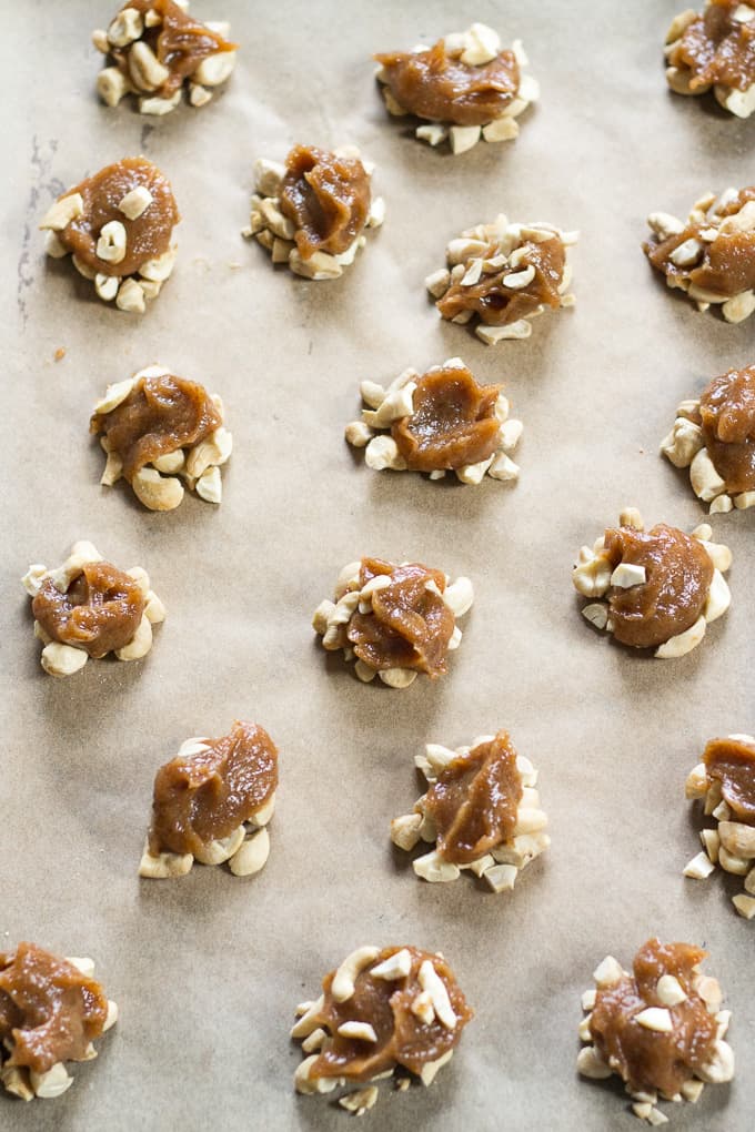 caramel and cashew clusters scattered on a piece of parchment paper