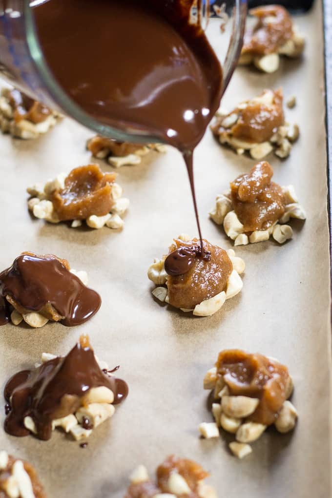 Chocolate being drizzled over a cashew caramel cluster