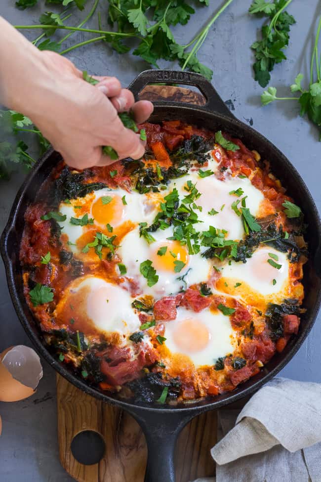 Eggs simmer in a spicy tomato sauce with kale and sausage in this savory and filling Shakshuka. This Paleo and Whole30 Shakshuka makes a comforting and healthy meal for brunch, dinner, or whenever!