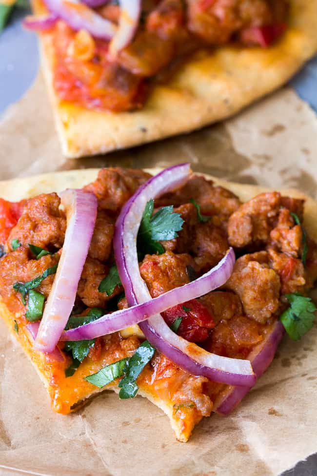 This hearty Paleo pizza has a thin, crisp and chewy crust with a sausage and fresh tomato basil topping that you can make spicy or mild to suit your tastes. The perfect filling and healthy pizza to make when a craving hits! Perfect 30 minute dinner for pizza night! Gluten free, dairy free, grain free, Paleo.