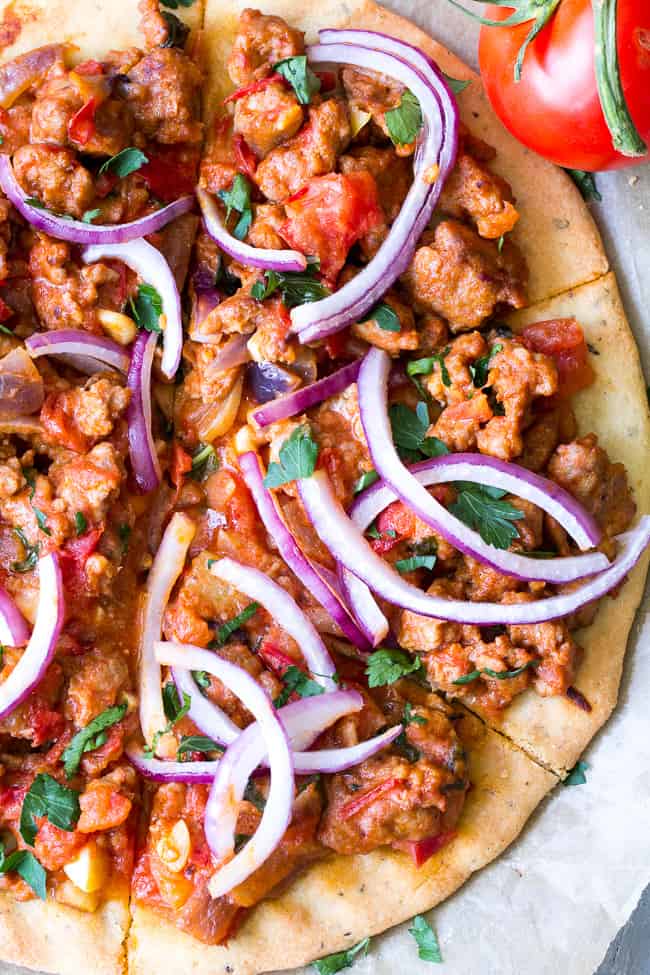 This hearty Paleo pizza has a thin, crisp and chewy crust with a sausage and fresh tomato basil topping that you can make spicy or mild to suit your tastes. The perfect filling and healthy pizza to make when a craving hits! Perfect 30 minute dinner for pizza night! Gluten free, dairy free, grain free, Paleo.