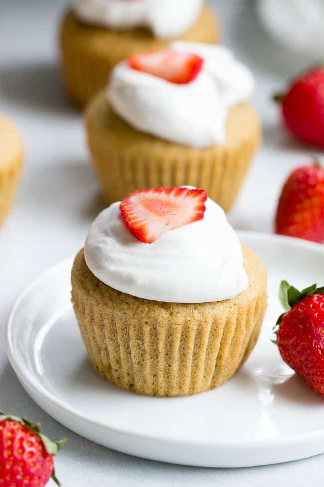 These Strawberry Shortcake Cupcakes start with a perfect paleo vanilla cupcake, filled with honey sweetened strawberry preserves and topped with thick and creamy coconut whipped cream. They're gluten free, dairy free, kid approved, fun to make, and perfect for any special occasion or holiday!