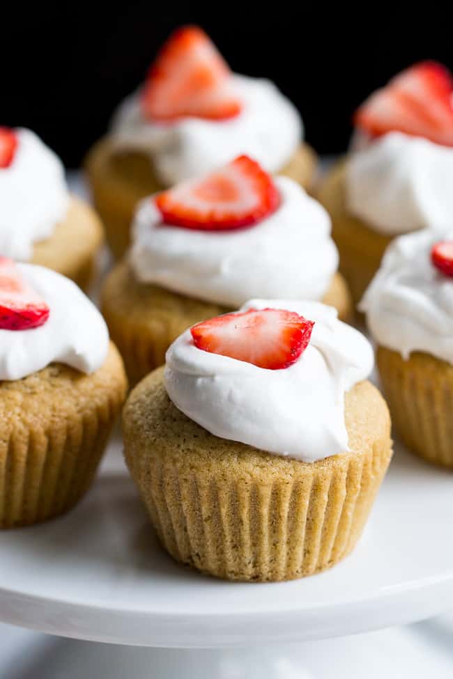 These Strawberry Shortcake Cupcakes start with a perfect paleo vanilla cupcake, filled with honey sweetened strawberry preserves and topped with thick and creamy coconut whipped cream. They're gluten free, dairy free, kid approved, fun to make, and perfect for any special occasion or holiday!