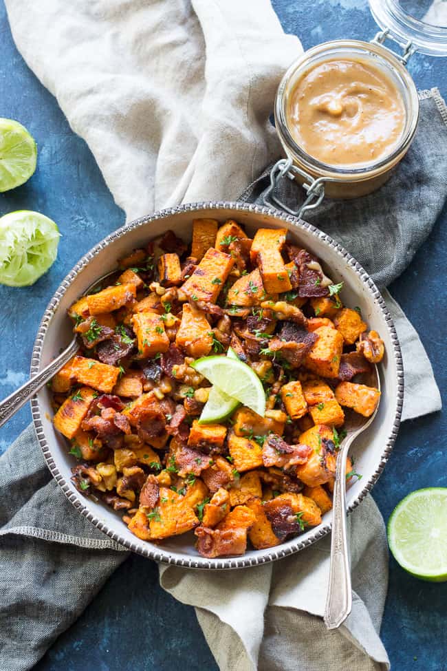 bowl of roasted sweet potato salad with two serving spoons and vinaigrette on the side