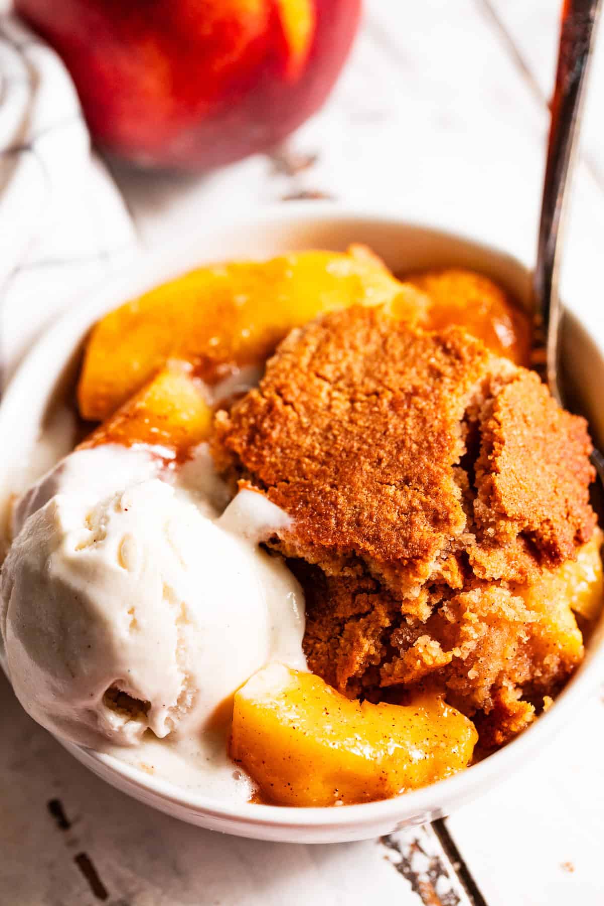 easy peach cobbler in a bowl with melting ice cream