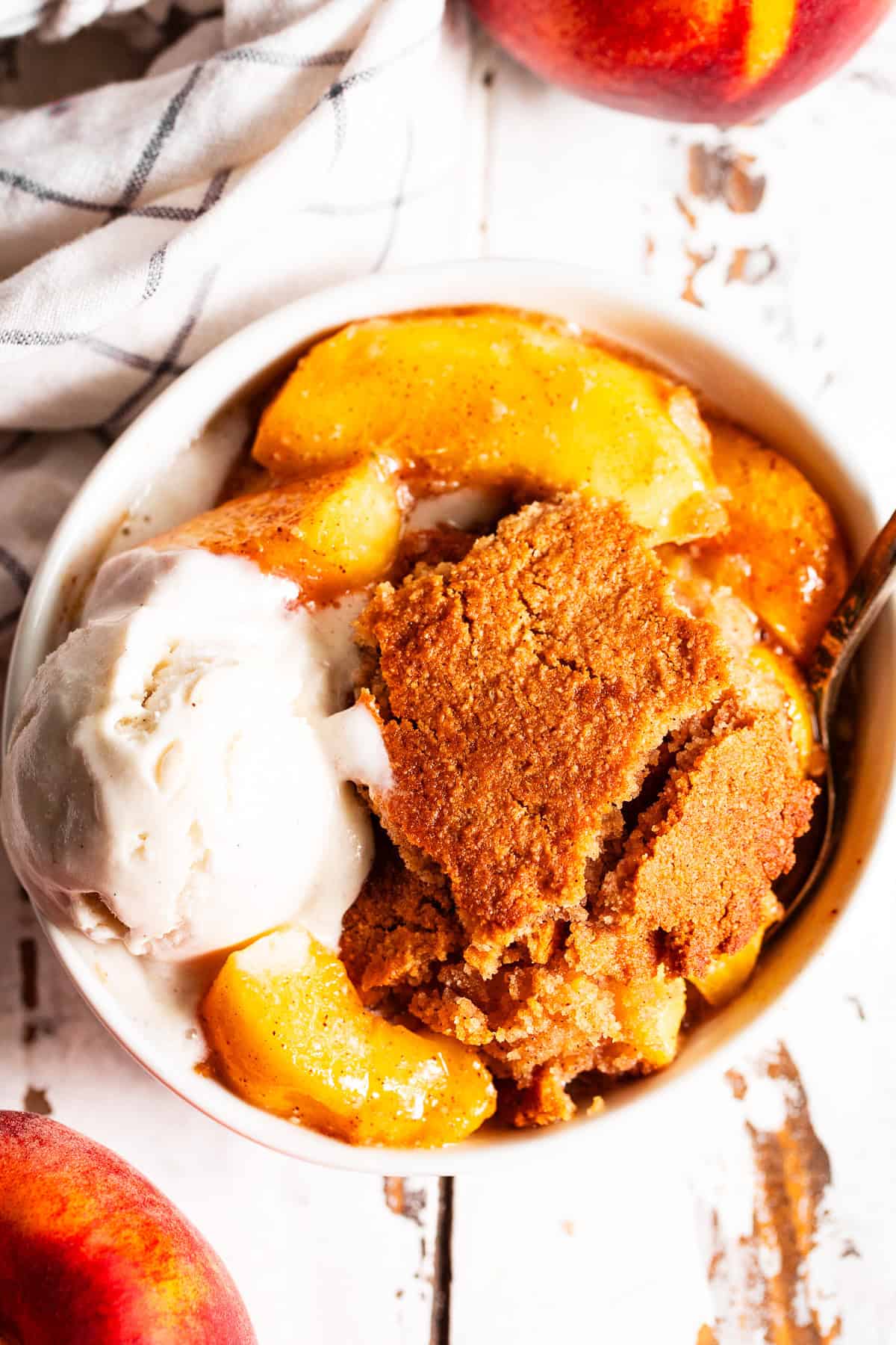 easy peach cobbler in a bowl with a scoop of melting ice cream