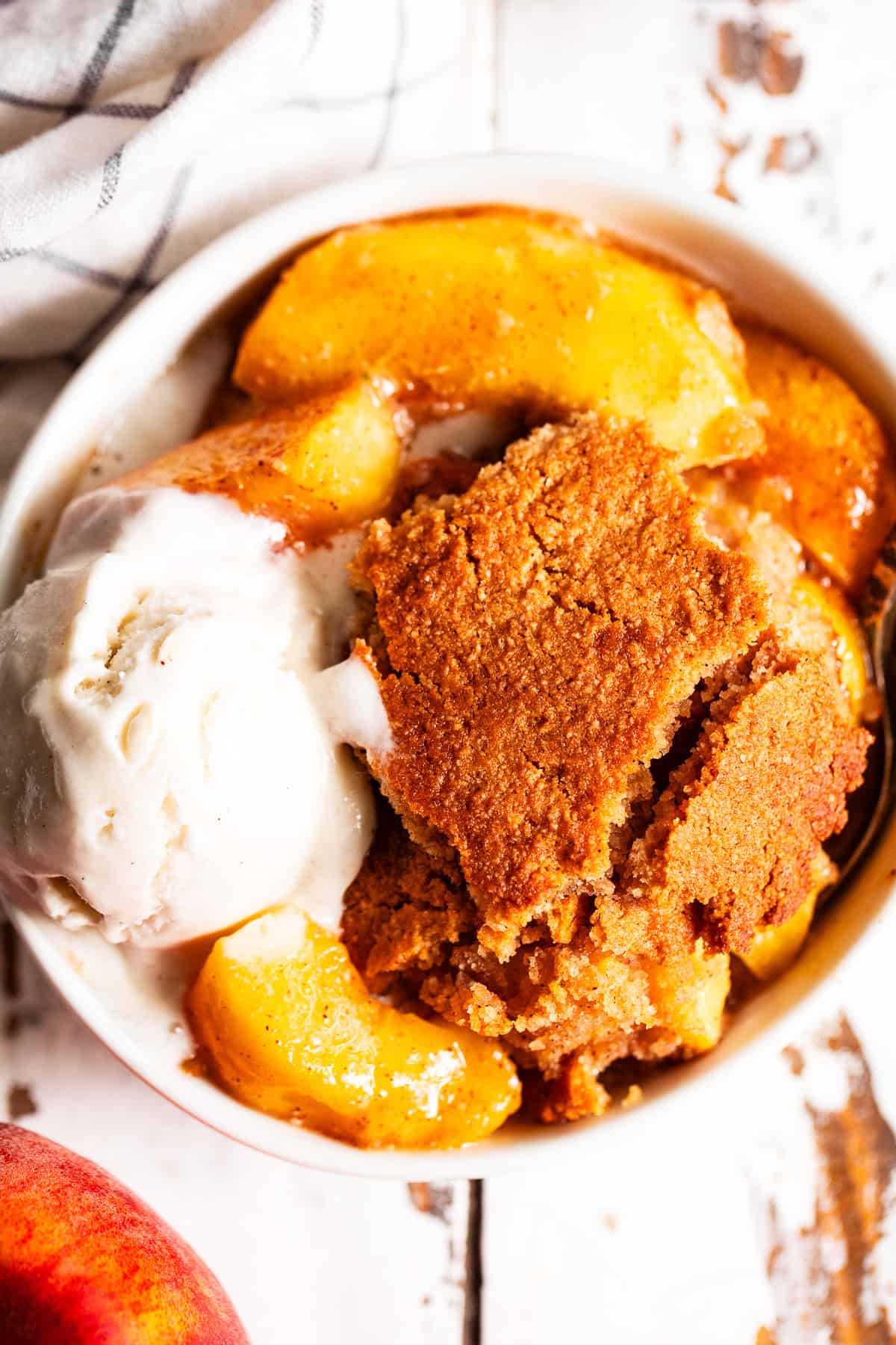 easy peach cobbler in a bowl with melting ice cream