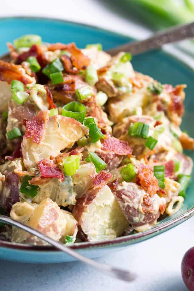 This creamy ranch potato salad is loaded with savory crispy bacon, green onions and couldn't be easier to make!  A homemade Paleo and Whole30 ranch dressing gives this potato salad a zesty, addicting "cheesy" flavor even though it's dairy-free!   