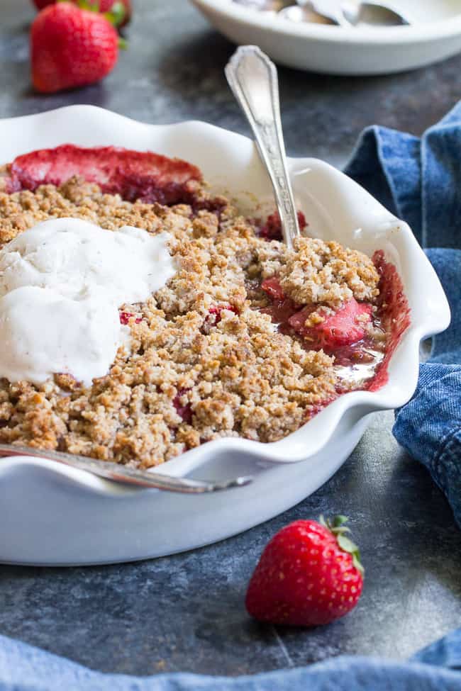 This paleo & vegan strawberry crumble couldn't be easier or more delicious! Made without refined sugar, grains, or dairy, it's a healthy summer dessert that will make everyone happy. A big scoop of coconut vanilla ice cream makes it the perfect treat! Gluten-free, dairy-free, paleo and vegan.