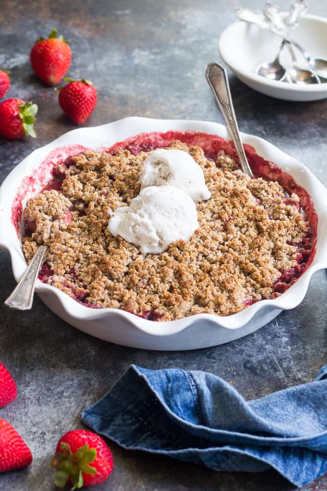 This paleo & vegan strawberry crumble couldn't be easier or more delicious! Made without refined sugar, grains, or dairy, it's a healthy summer dessert that will make everyone happy. A big scoop of coconut vanilla ice cream makes it the perfect treat! Gluten-free, dairy-free, paleo and vegan.