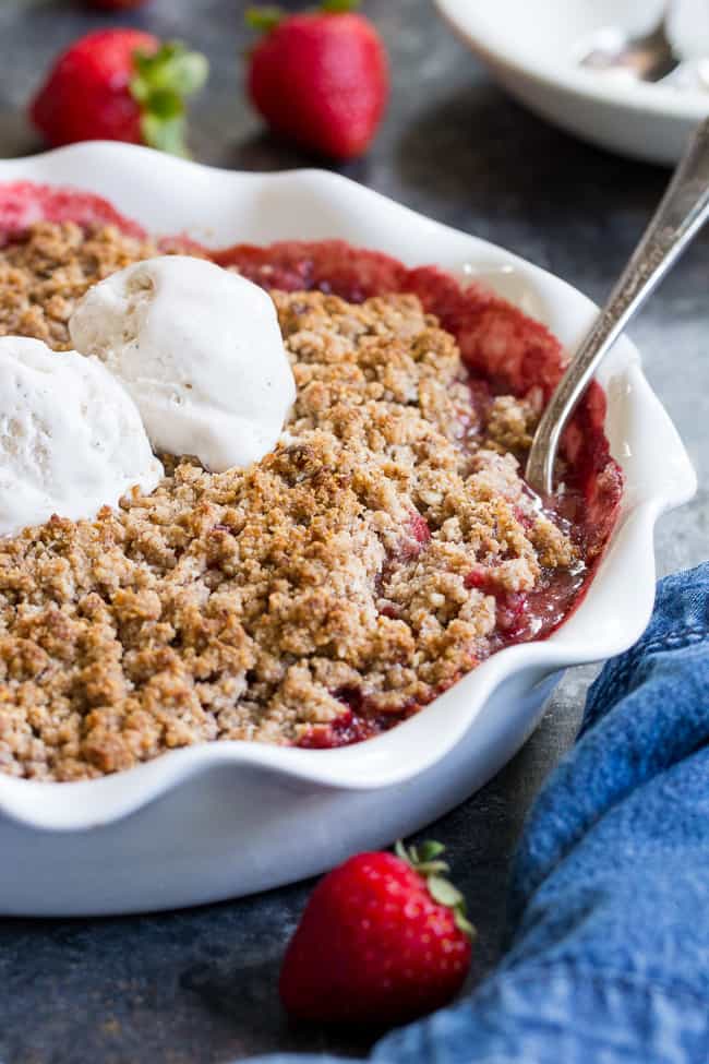 This paleo & vegan strawberry crumble couldn't be easier or more delicious! Made without refined sugar, grains, or dairy, it's a healthy summer dessert that will make everyone happy. A big scoop of coconut vanilla ice cream makes it the perfect treat! Gluten-free, dairy-free, paleo and vegan.