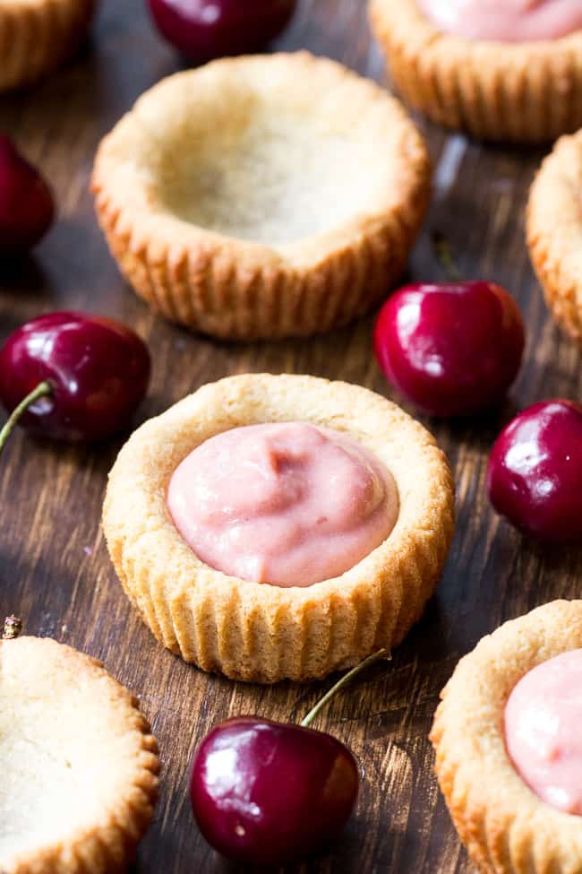 Thick, creamy and sweet cherry curd made from fresh cherries is spooned into grain free and paleo cookie tarts for a delicious, fun and secretly healthy dessert!   Dairy free, refined sugar free, gluten-free and paleo.