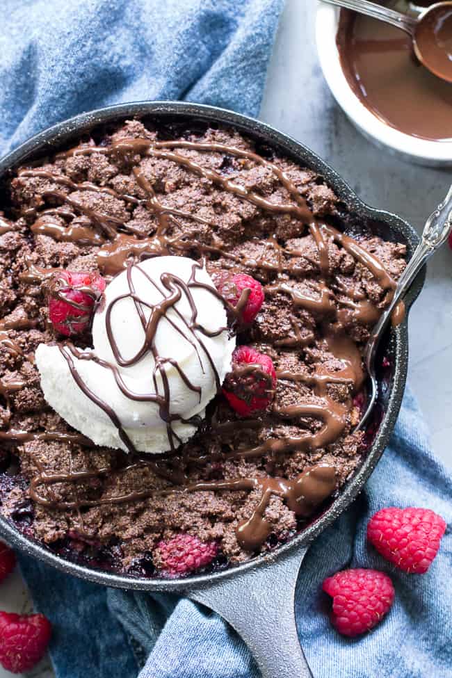 This raspberry chocolate crumble is super easy to make, paleo, vegan, and can be served right out of the skillet!   It's extra tasty topped with melted chocolate and coconut vanilla ice cream.   Gluten free, refined sugar free, dairy free.