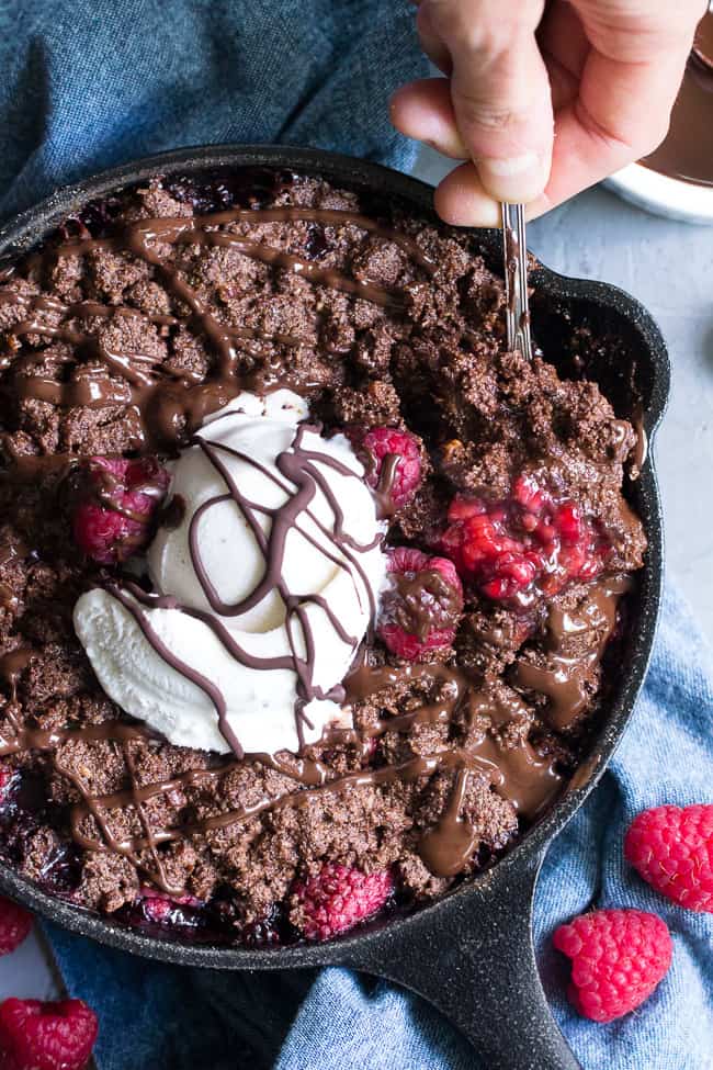 This raspberry chocolate crumble is super easy to make, paleo, vegan, and can be served right out of the skillet!   It's extra tasty topped with melted chocolate and coconut vanilla ice cream.   Gluten free, refined sugar free, dairy free.