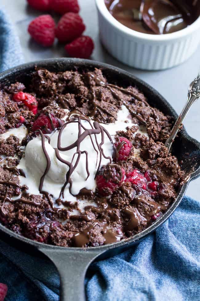 This raspberry chocolate crumble is super easy to make, paleo, vegan, and can be served right out of the skillet!   It's extra tasty topped with melted chocolate and coconut vanilla ice cream.   Gluten free, refined sugar free, dairy free.