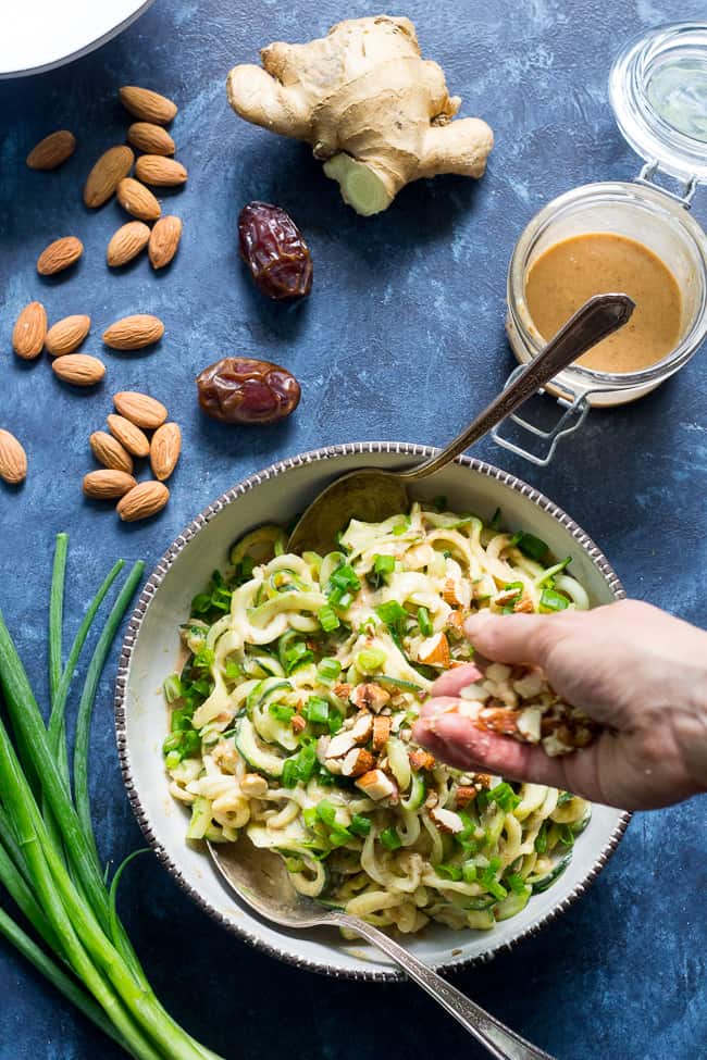 These almond butter sesame zucchini noodles are a delicious healthy makeover of classic sesame peanut noodles!  The creamy almond butter sauce is sweetened just the right amount with dates and loaded with chopped almonds and scallions.  Paleo, Whole30, and Vegan too! 