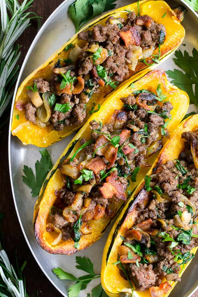 Delicata squash is roasted to perfection and stuffed with ground beef, caramelized onions, bacon, spinach, mushrooms and seasonings.  This cozy paleo and Whole30 stuffed squash is great for any meal or as a side dish.   Savory, filling and healthy!