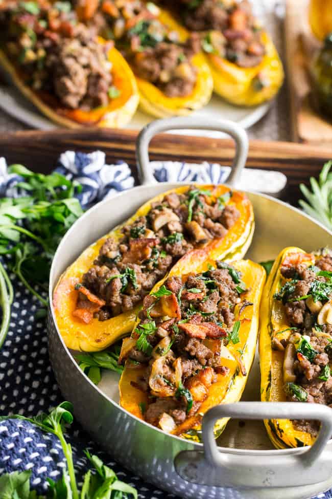 Delicata squash is roasted to perfection and stuffed with ground beef, caramelized onions, bacon, spinach, mushrooms and seasonings.  This cozy paleo and Whole30 stuffed squash is great for any meal or as a side dish.   Savory, filling and healthy!