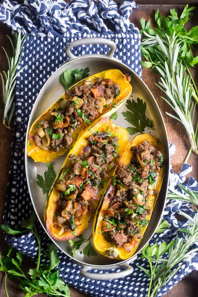 Delicata squash is roasted to perfection and stuffed with ground beef, caramelized onions, bacon, spinach, mushrooms and seasonings.  This cozy paleo and Whole30 stuffed squash is great for any meal or as a side dish.   Savory, filling and healthy!