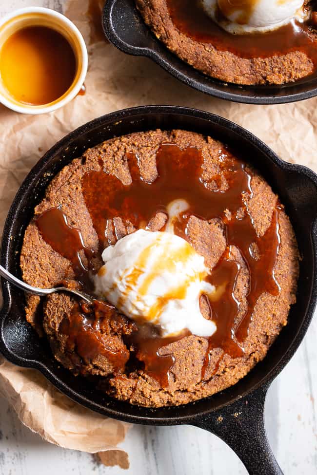 This fudgy pumpkin snickerdoodle skillet cookie is loaded with pumpkin spice and cinnamon, drizzled with dairy-free salted caramel sauce and topped with coconut vanilla ice cream.  This rich paleo dessert is perfect for fall and the holiday season!  Kid approved, paleo, dairy-free, grain-free.