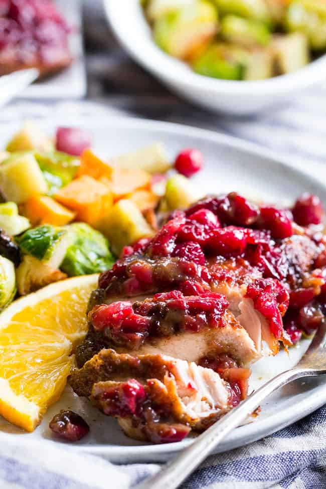 We take crisp, savory spiced chicken thighs and a healthy, refined sugar free orange cranberry sauce and bake them together to delicious perfection!  This Paleo Orange Cranberry Chicken is easy to make, gluten-free, dairy-free, and has a Whole30 friendly option.