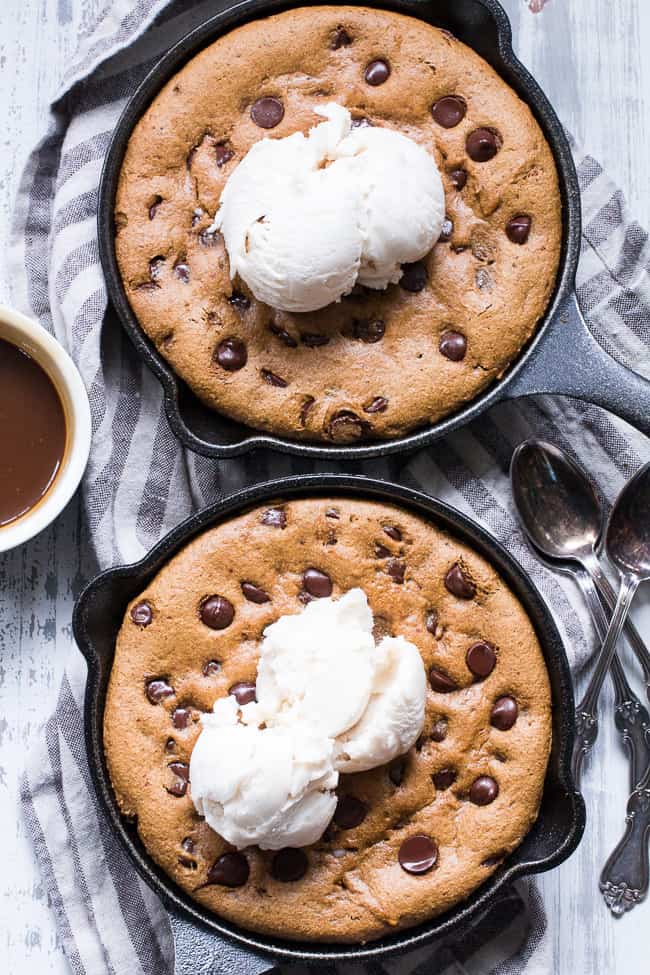 two chocolate chip cookies skillets with scoops of white ice cream 