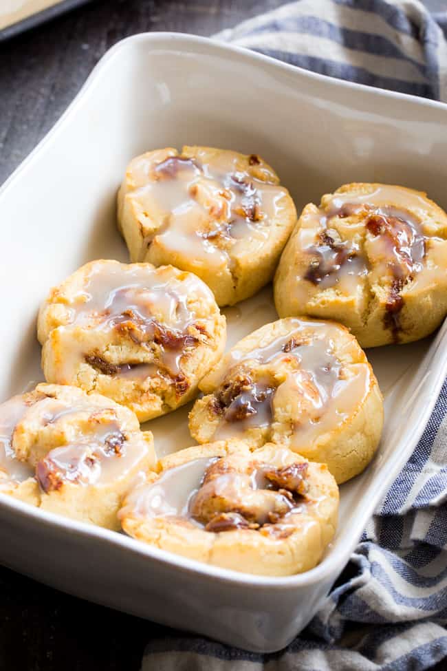 a baking dish with 6 cinnamon rolls drizzled with white icing